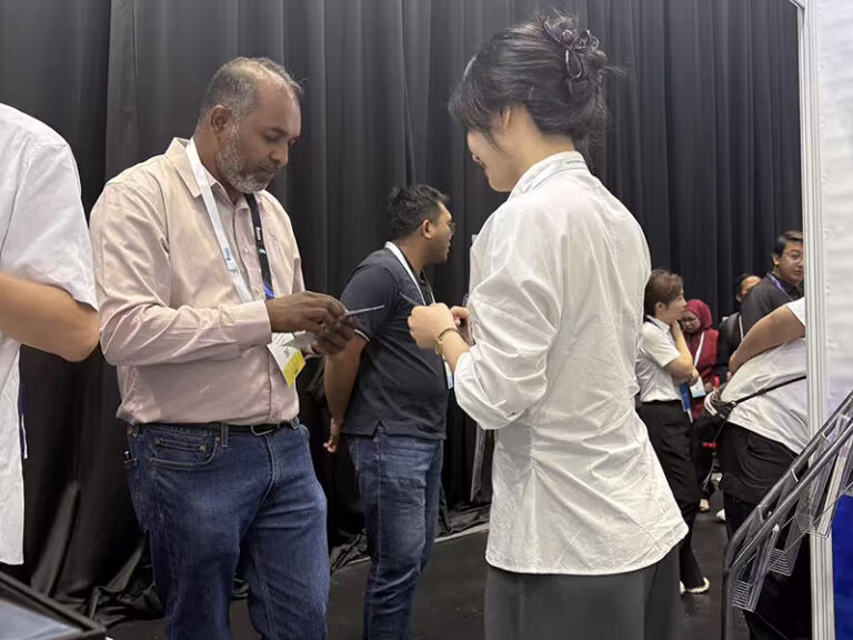shenhai sales representative exchanging business cards with client at oga 2026